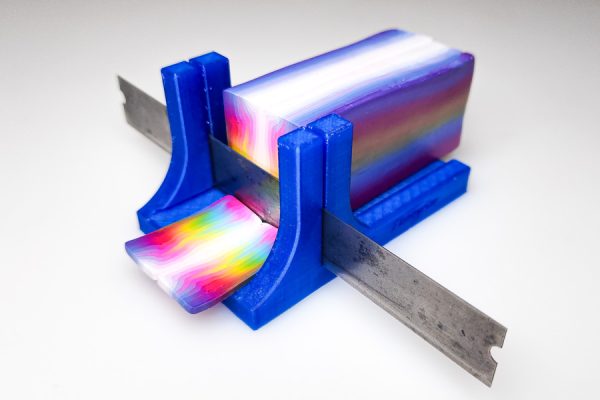 3D printed polymer clay slicer by Hobbyrian having just sliced a rainbow cane.