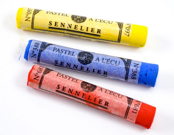 Three Sennelier soft pastel sticks, one yellow, one blue, one red. 