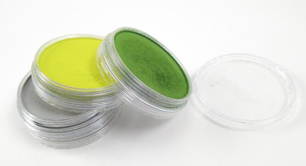 Several pans of Pan Pastel, a type of soft pastel, stacked haphazardly, showing the colors inside the pans.