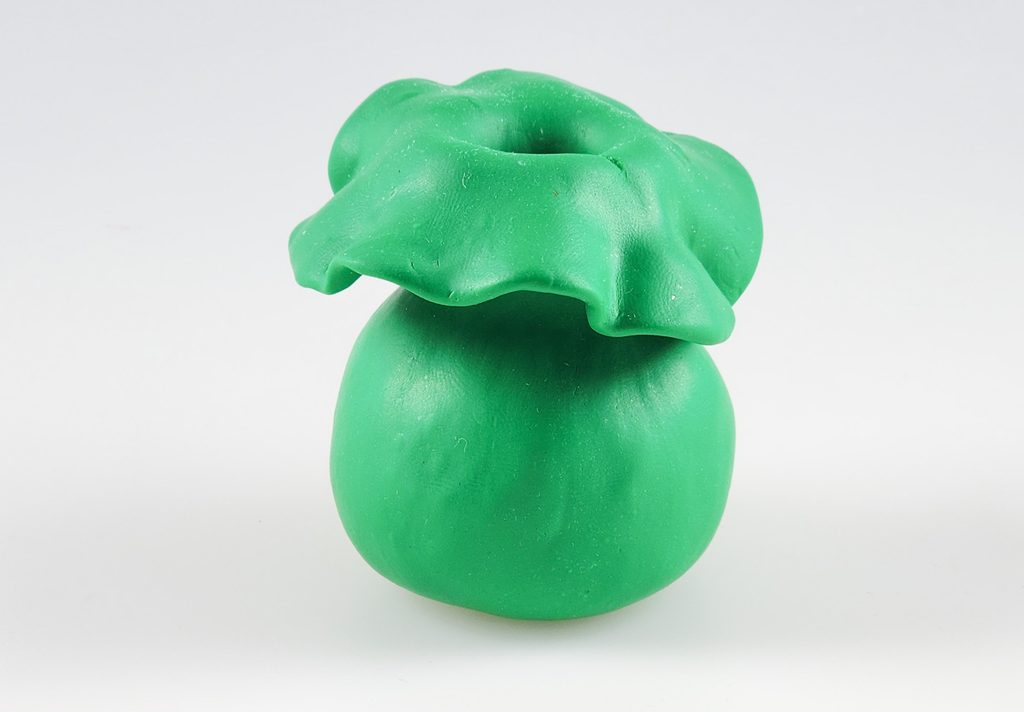 Green vase made from Du-kit polymer clay using the pinch pot technique. The lip of the vase has sagged during baking.